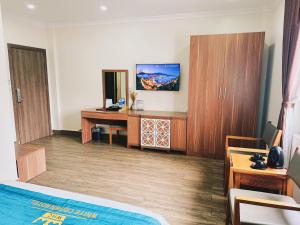 a room with a bed and a desk and cabinets at White Crown Hotel Ha Long in Ha Long
