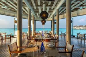 a restaurant on the beach with tables and chairs at Niva Kuramathi Maldives in Rasdhoo