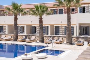 a hotel with palm trees and a swimming pool at Rose Bay Hotel in Kamari