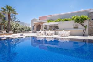 a swimming pool with chairs and a building at Rose Bay Hotel in Kamari