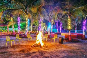 a campfire with chairs and palm trees and lights at Falcon's Retreat in Pune