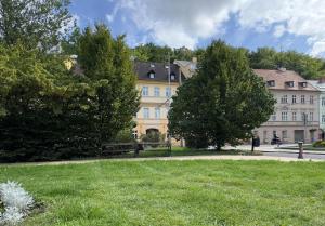 a large yellow building with trees and a park at Hotel PAYER in Teplice