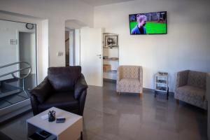 a living room with two chairs and a tv on the wall at Hotel PAYER in Teplice