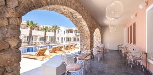 a restaurant with a pool and tables and chairs at Rose Bay Hotel in Kamari +37 photos
