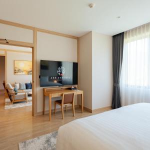 a hotel room with a bed and a desk with a television at Zen Essence Khao Yai in Khao Yai