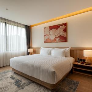 a hotel room with a large bed with white sheets at Zen Essence Khao Yai in Khao Yai