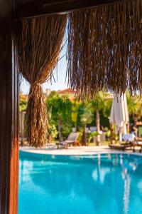a view of a swimming pool with a straw umbrella at Triangulo Hotel in Alaçatı