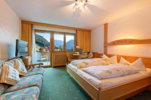 ein Schlafzimmer mit Bett, Fernseher und Sofa in der Unterkunft Hotel Thaneller Stadl Bräu in Berwang + 43 Fotos