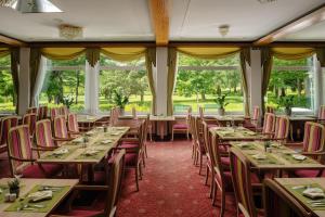 a dining room with tables and chairs and windows at Hotel PALACE in Bad Hofgastein