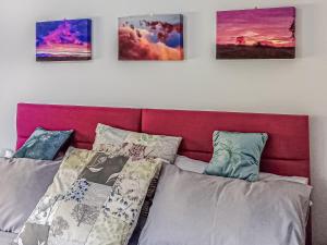 a bed with a red headboard and four pictures on the wall at The Pavilion in Swaton