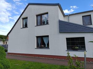 a white house with four windows with curtains at Haus Berta in Spremberg