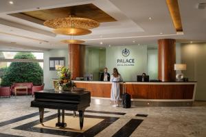 a woman standing at the lobby of a hotel with a piano at Hotel PALACE in Bad Hofgastein +45 photos