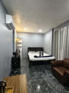 a room with a bed and a television and a couch at Travis Post Homestay in Siquijor