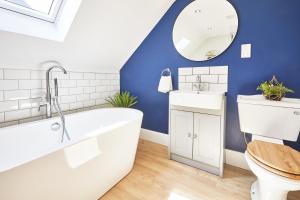 a bathroom with a white tub and a blue wall at The Penthouse Retreat in Whitby