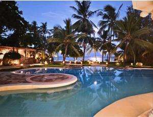 a swimming pool with palm trees and the ocean at Soroi Blue - Diani Beach in Diani Beach