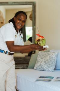 a woman standing next to a bed holding a dessert at Soroi Blue - Diani Beach in Diani Beach +52 photos