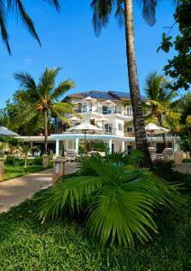 a large white building with palm trees in front of it at Soroi Blue - Diani Beach in Diani Beach