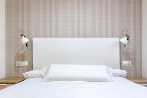 a white bed with two lights on top of it at Beach Palo Malaga in Málaga +1 photo