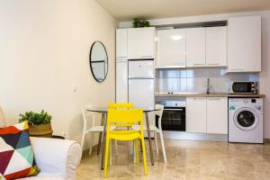 a kitchen with a table and yellow chairs in a room at Beach Palo Malaga in Málaga
