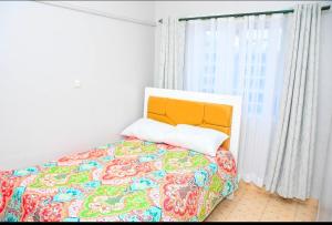 a bedroom with a bed with a colorful blanket and a window at Comfort Inn Nyeri in Nyeri
