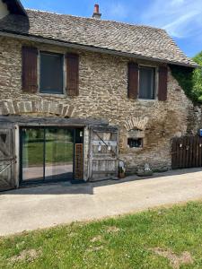 a stone house with a large sliding garage door at Les Groseilliers in Moyrazès