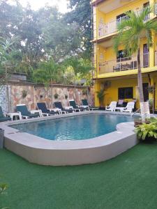 a swimming pool with chairs and a building at Phratamnak Inn Hotel & Guesthouse - 100 mtr from the beach in Pattaya South