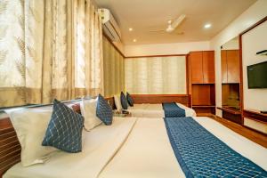 a hotel room with two beds and a flat screen tv at Uddhav Vilas A Family Hotel in Udaipur