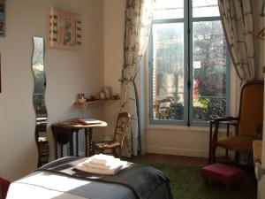 a room with a bed and a window and a table at La Maison Du Marchand in Peyrat-le-Château