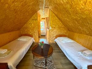 two beds in a room with a table at Rezo's Ranch Cottage in Samtredia
