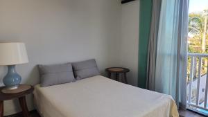 a bedroom with a bed with two tables and a window at Casa Casal Itapoá in Itapoa