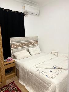 a bedroom with a large bed with white sheets at Phoenix Pyramids Inn in Banī Ghālib