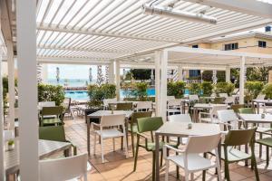 a restaurant with tables and chairs and a pool at Dorisol Mimosa Studio Hotel in Funchal