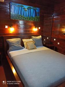 a large bed in a room with wooden walls at Chalet Bois Luxe in Nosy Be