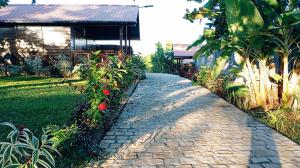 a brick path in front of a house with flowers at Chalet Bois Luxe in Nosy Be