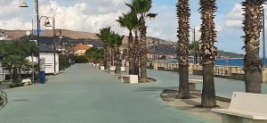 a walkway with palm trees and benches on a beach at Tronca Apartament Kalabria in Marina di Strongoli