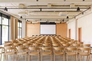 a room with a lecture hall with chairs and a screen at Hotel Node in Swarzędz