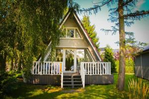 a small tree house with a porch and a white railing at Sobie-Wyspa Domki pod Brzozami in Gdańsk