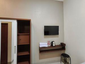 a hotel room with a television on the wall at Teras Watu Tegal in Tegal +13 photos