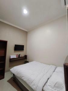 a bedroom with a white bed and a tv at Teras Watu Tegal in Tegal