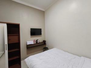 a bedroom with a bed and a flat screen tv at Teras Watu Tegal in Tegal