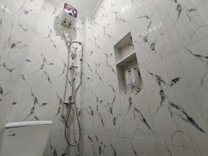 a shower in a bathroom with a marble wall at Teras Watu Tegal in Tegal