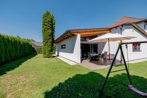 a white house with an umbrella and a yard at Freiraum Urlaubsapartment in Villach