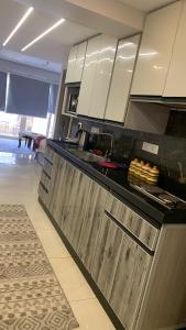 a kitchen with white cabinets and a black counter top at بورتو السخنه الاهرامات in Ain Sokhna