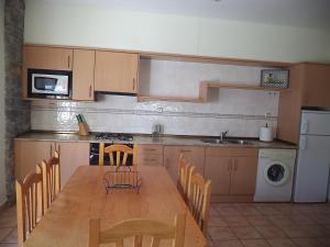 a kitchen with a wooden table with chairs and a sink at Casa la Cuadreta in Calvera
