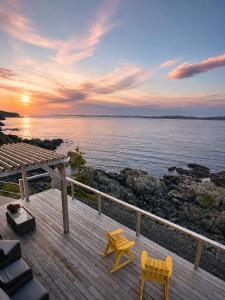 a wooden deck with two chairs and a view of the water at The View suites and breakfast in Triton, Newfoundland in Pilleyʼs Island