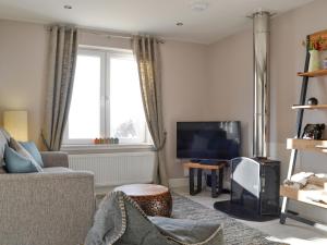 a living room with a couch and a television at Lily Lodge - Uk31958 in Dibaig