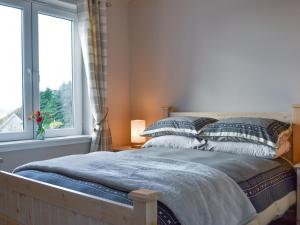 a bedroom with a bed with pillows and a window at Lily Lodge - Uk31958 in Dibaig +22 photos