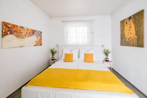 a white bedroom with a large bed with orange pillows at Freiraum Urlaubsapartment in Villach +37 photos