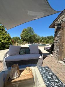a wicker couch sitting under an umbrella on a patio at Maison en pierre in Saint-Cyr