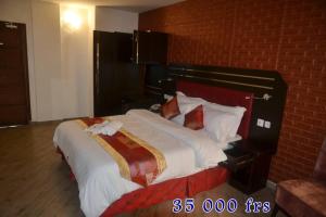 a large bed in a room with a brick wall at ALVI SEVEN Hotel in Douala